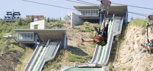 Man and woman riding down zip line at Utah Olympic Park