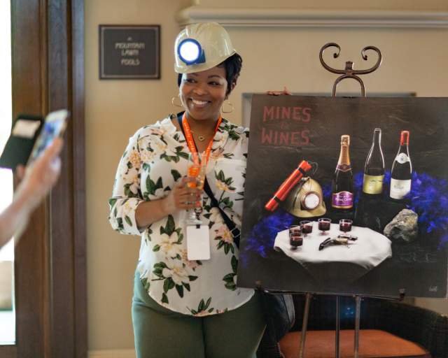 Woman next to a painting of wine