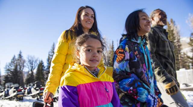 Family smiling and walking during snowmobiling tour