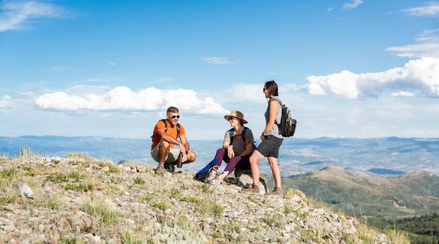 three hikers resting at the top of the mountain