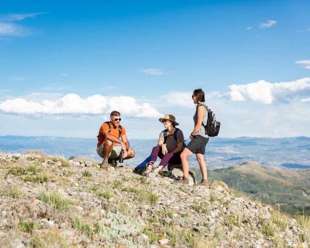 three hikers resting at the top of the mountain