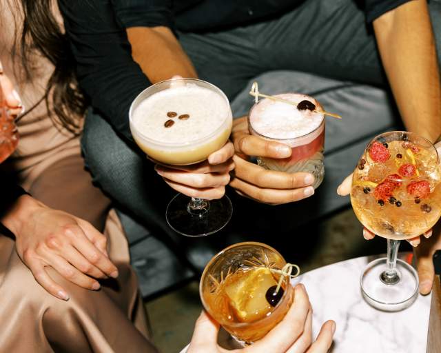 group of people holding a round of drinks