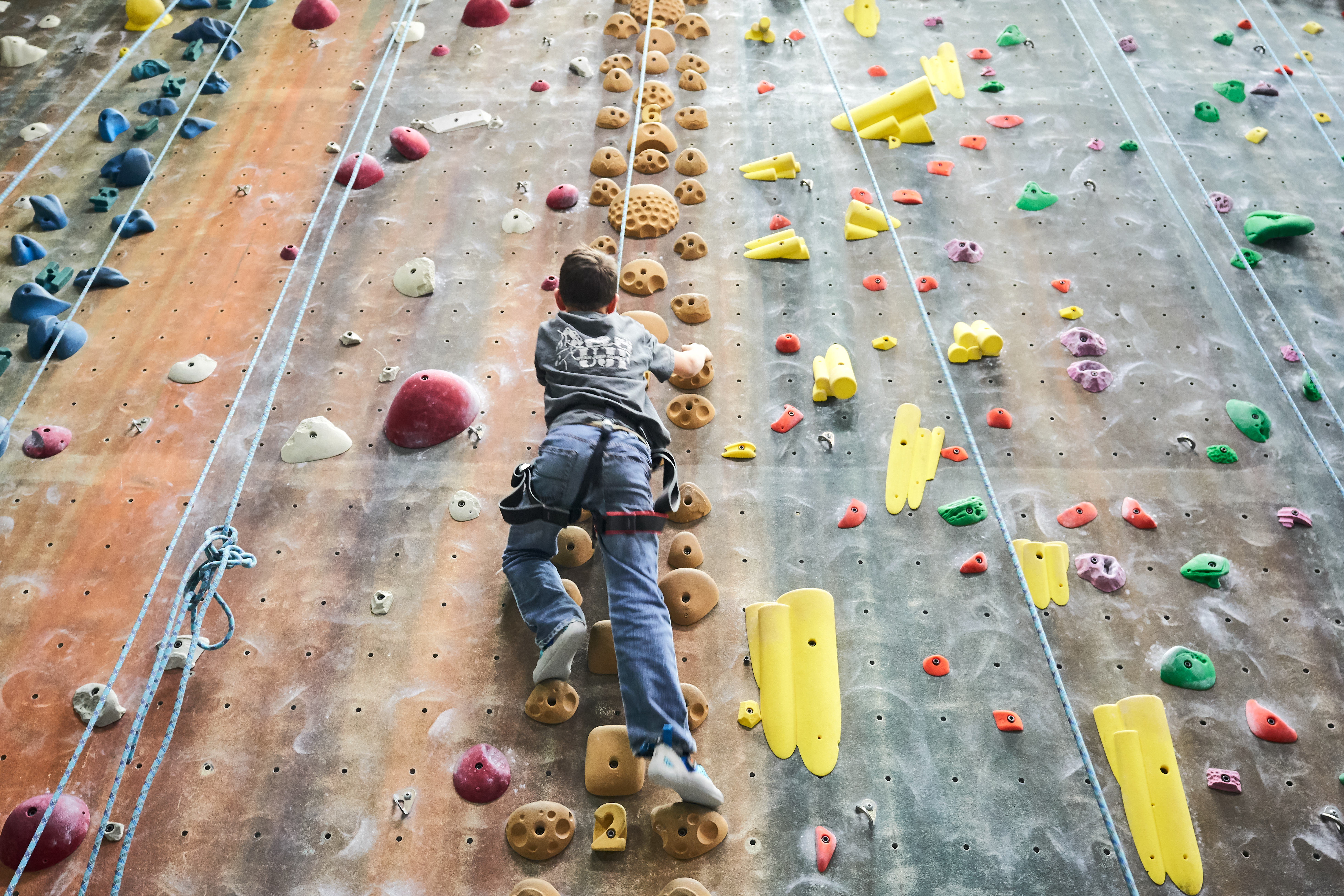 Boy climbing up a rock climbing wall