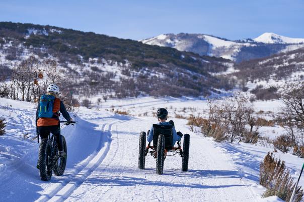 Two people fat tire biking on snow