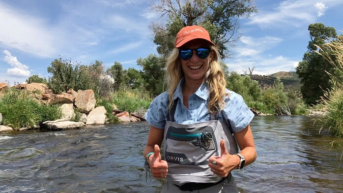 Fisherman gives two thumbs up while standing in a river