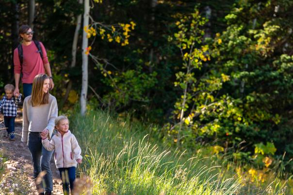 A family hikes on a trail in a forest near Park City, UT