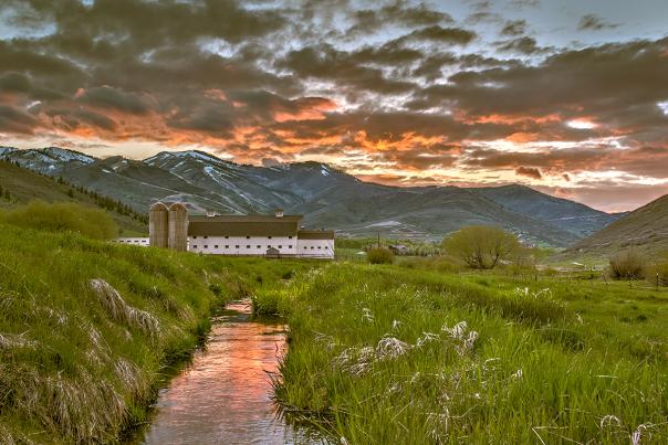 Scenic of a White Barn during a colorful Spring Sunset with mountains in the background