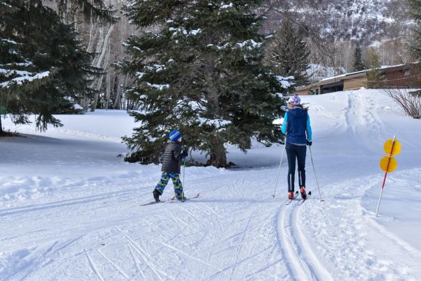 Young boy learning how to nordic ski with instructor