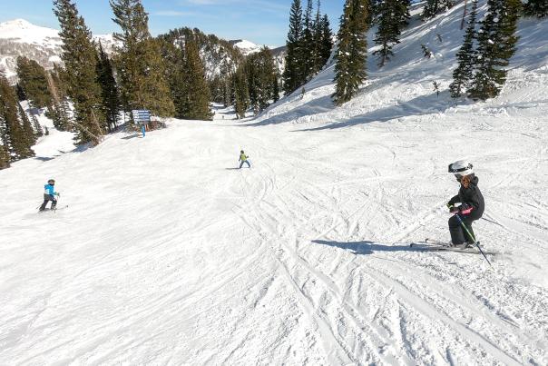 Three kids skiing down a mountain