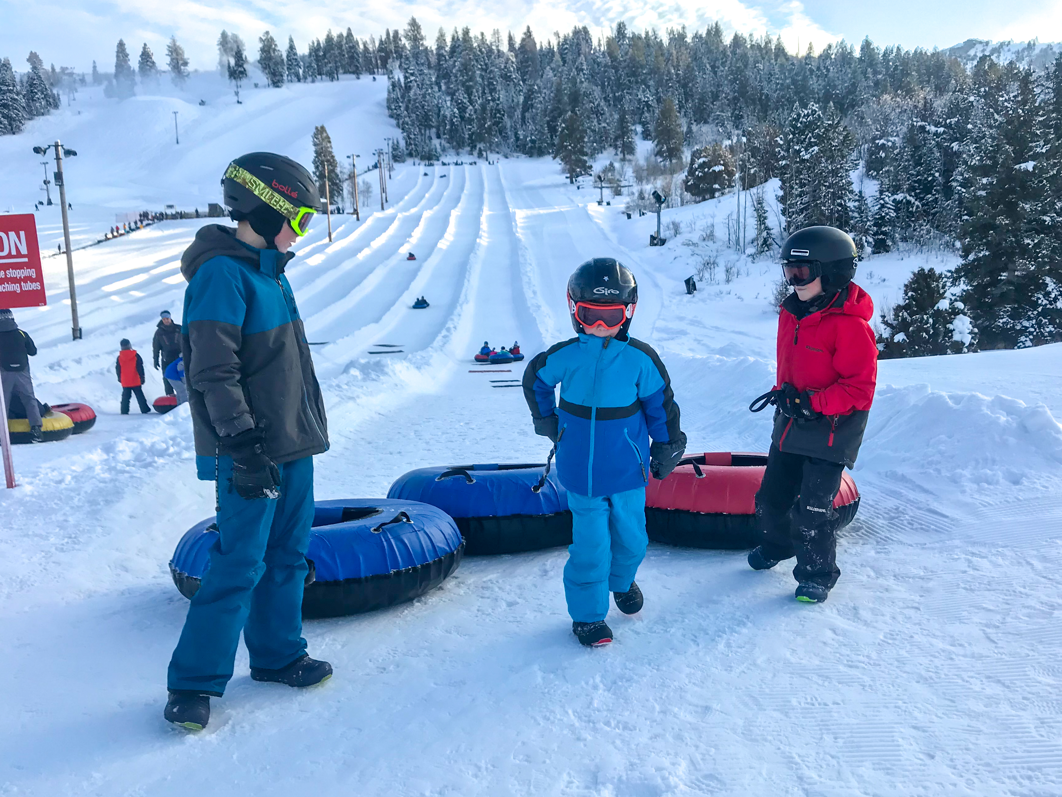 three boys standing at the end of the tubing lane with their with tubes