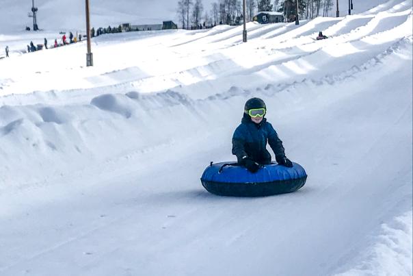 a boy rides a blue tube down a tubing lane in Park City