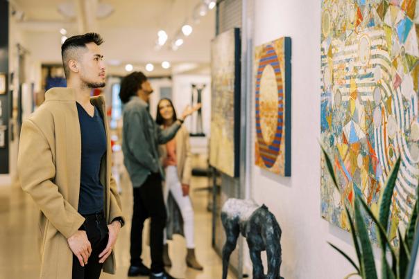 A man views an art piece on a wall in a well lit gallery in Park City, UT