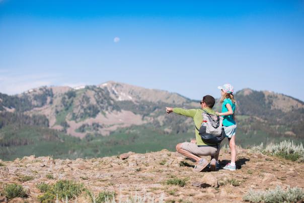 Father and young daughter looking at view from top of mountain