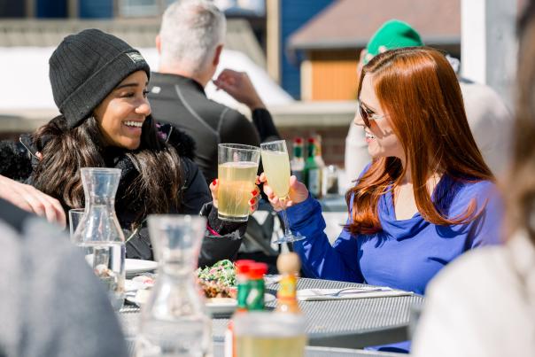 two girls cheers their drinks while outside