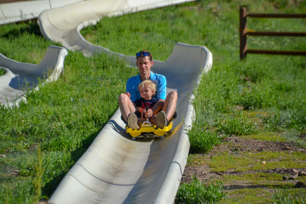 Father and Son ride down alpine slide together