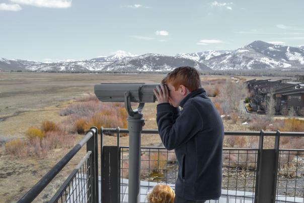 a child looking through binoculars at wetlands