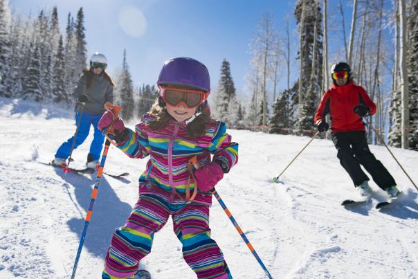 Young girl skiing with her parents