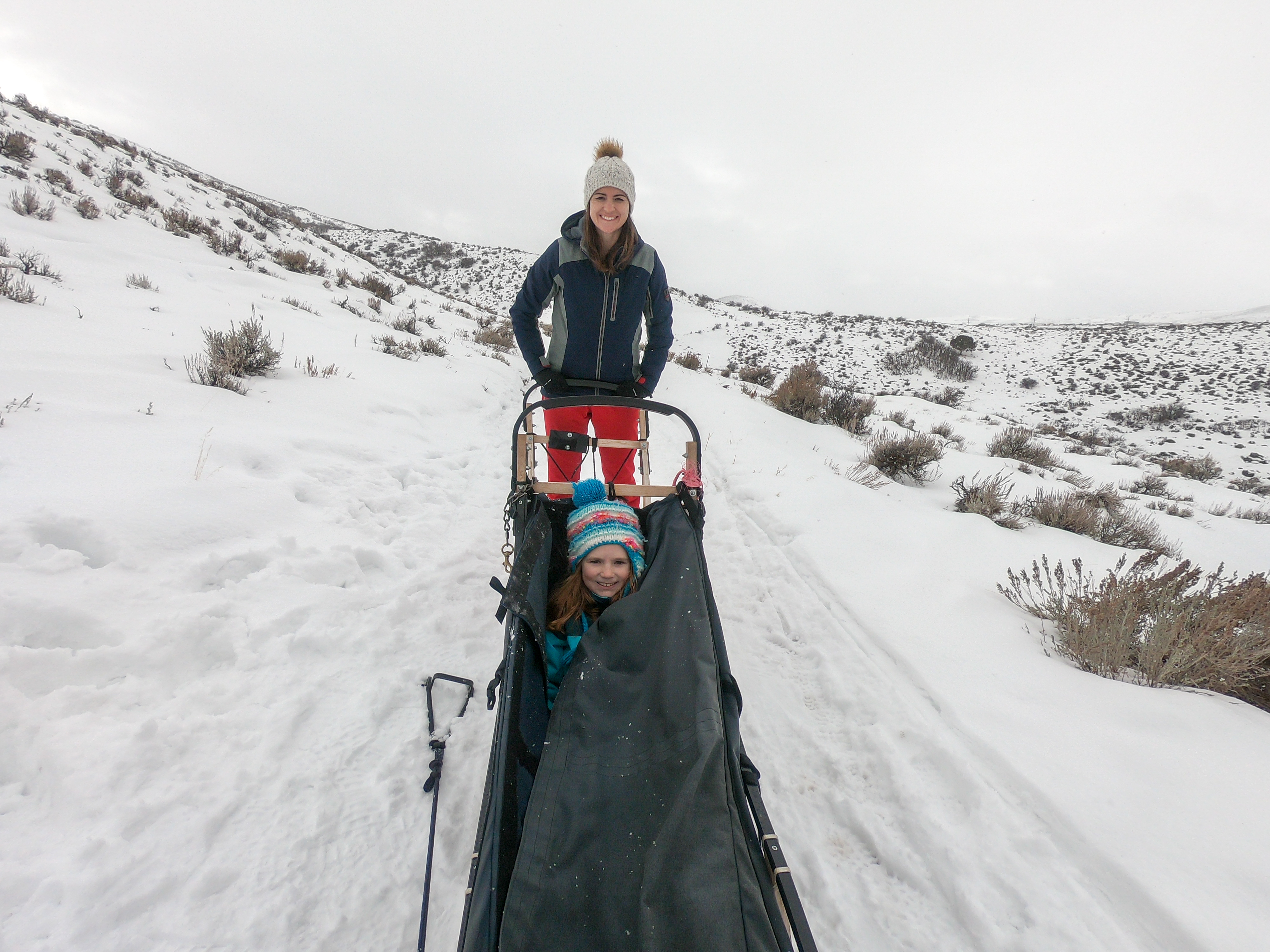 Mother and Daughter pose for photo on the dog sled in the snow of Park City