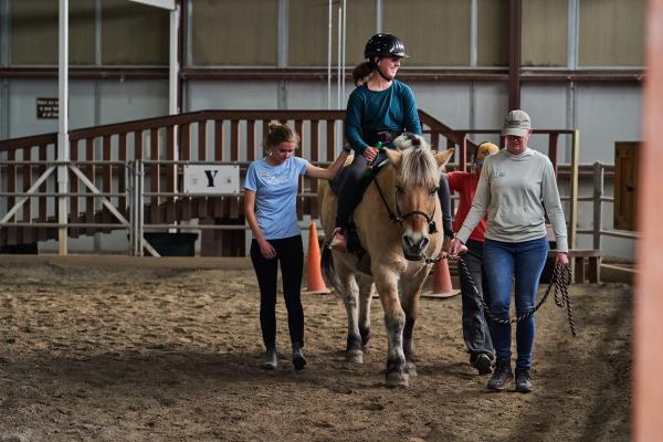 Girl riding a horse with guides walking next to horse