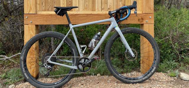 Grey gravel bike leaning against trail sign