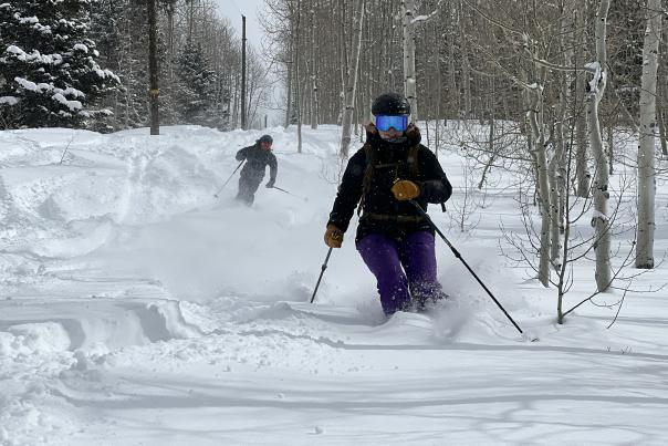 Two skiers make turns in powder snow on a ski run near Park City, UT