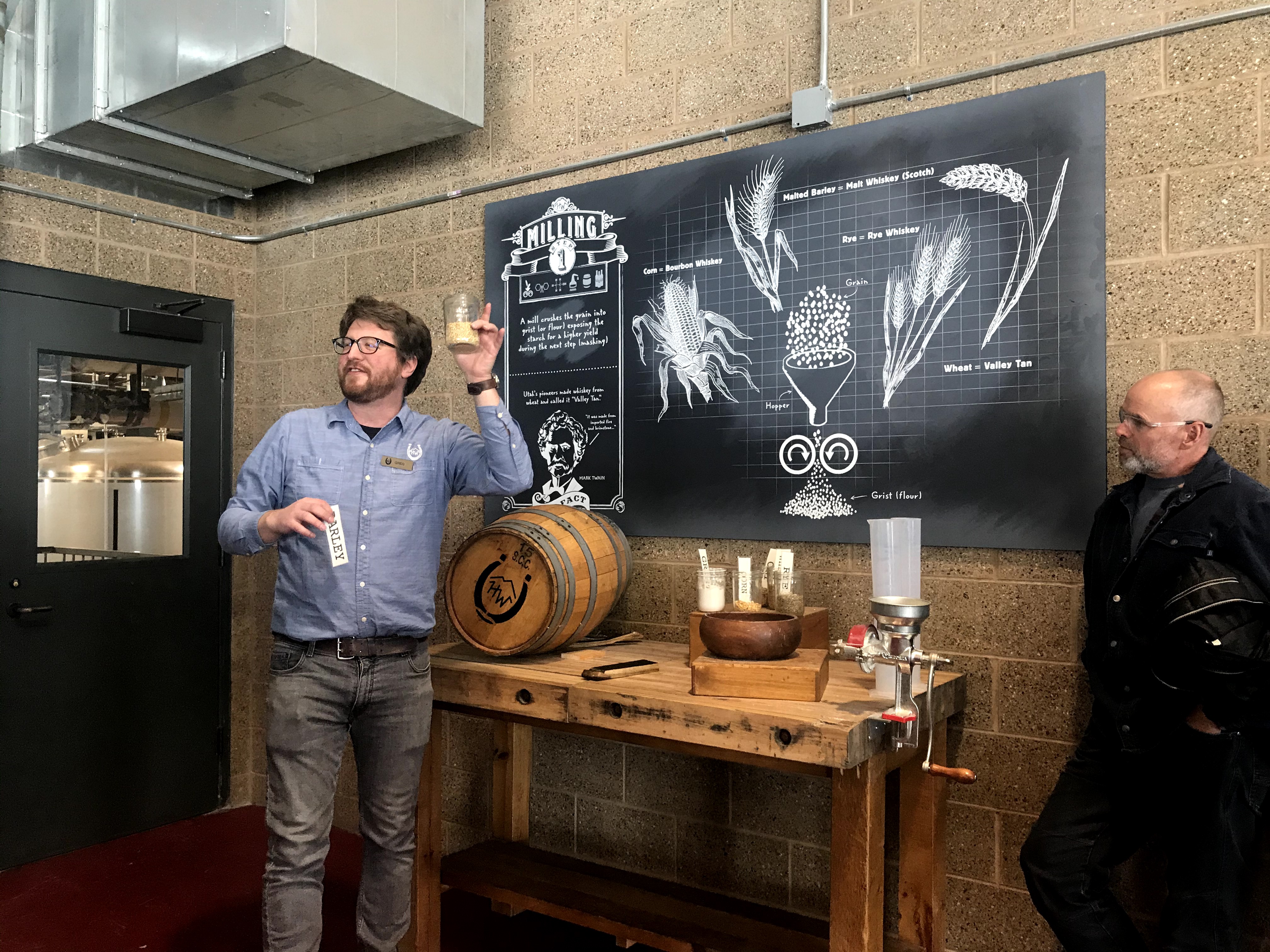 Tour guide explains the whiskey making process and holds up ingredients to the group