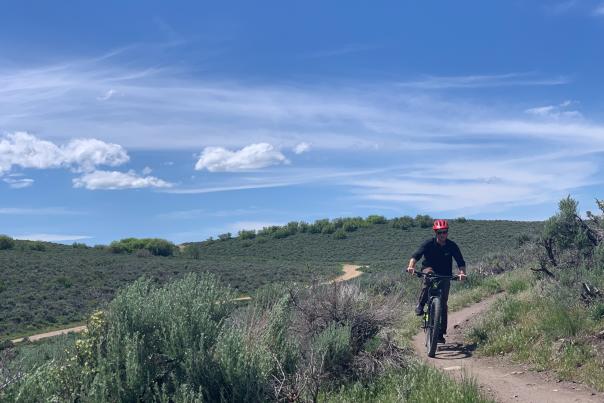 A guy riding a mountain bike with scenic mountain view in background