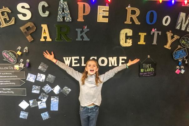 Girl stands in front of a sign that reads escape room