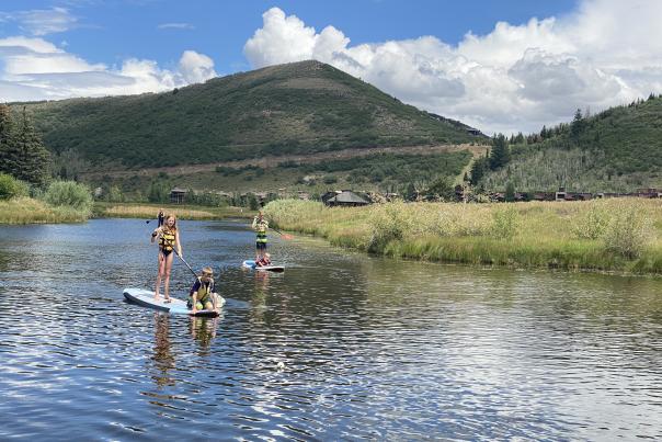 Three kids playing on stand up paddle boards