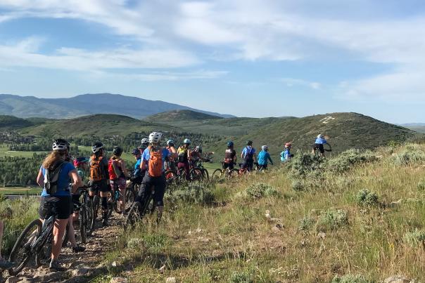 Women on mountain bikes in a line along a trail