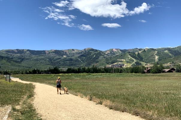 Woman walking with her dog with scenic mountains in background