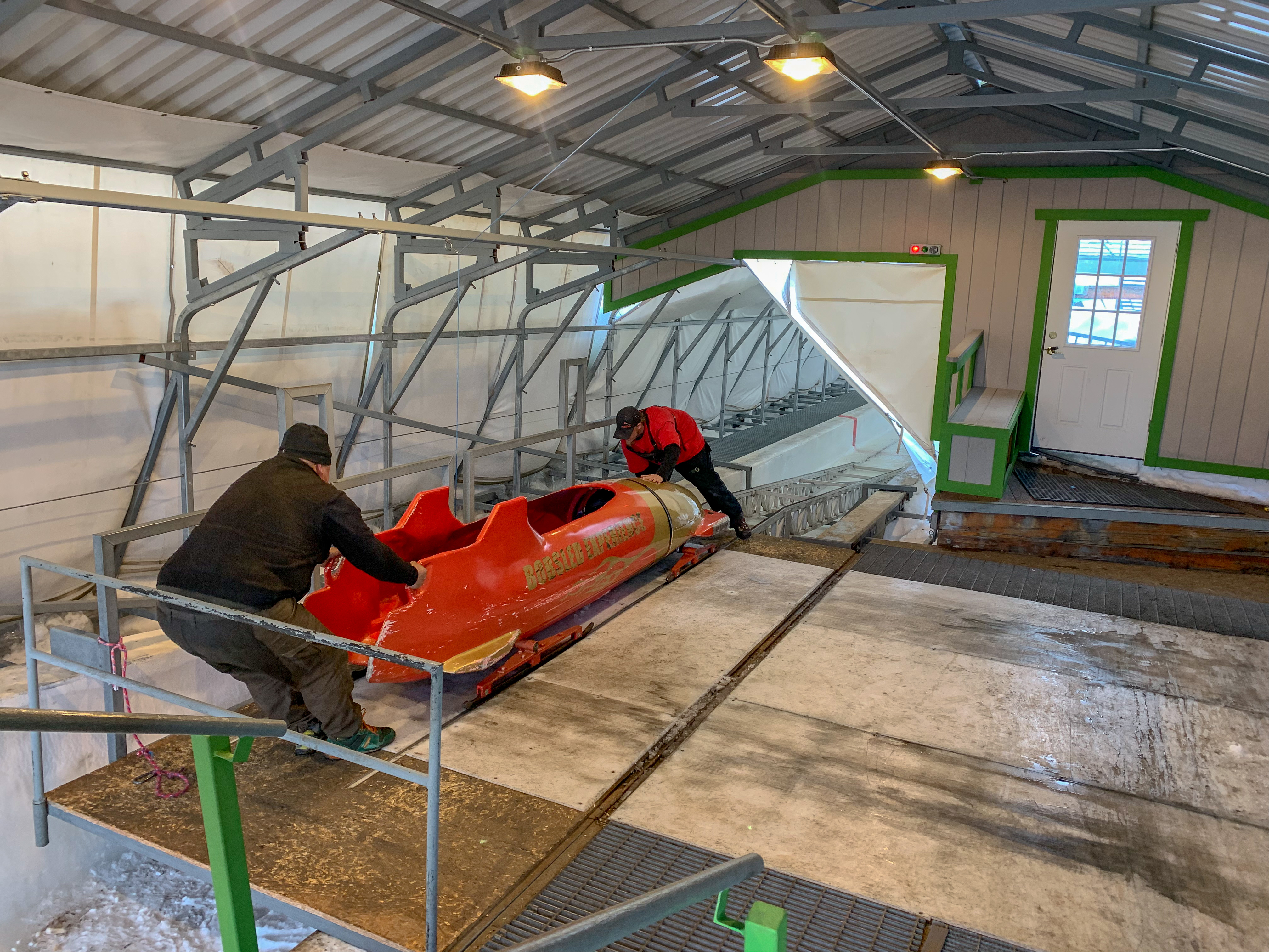 Two men load a bobsled onto the track