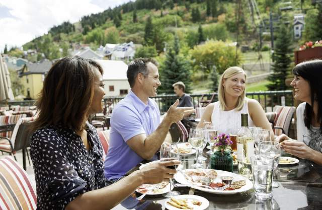 Group of adults eating lunch on patio near town lift in the summer