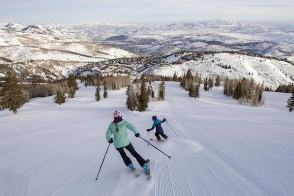 Mom and child skiing down a groomed trail