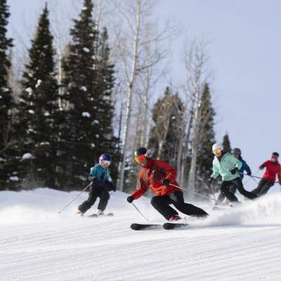 Family skiing down groomer run