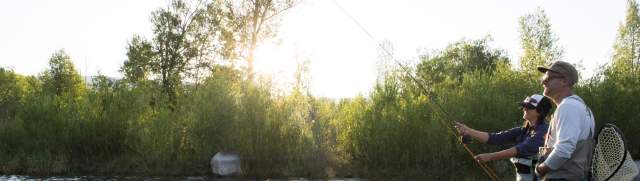 Man and woman fly fishing in the summer on the Provo River.