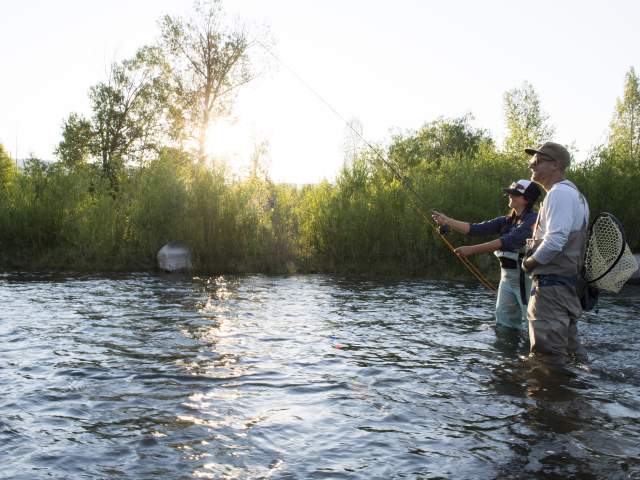 Man and woman fly fishing in the summer on the Provo River.