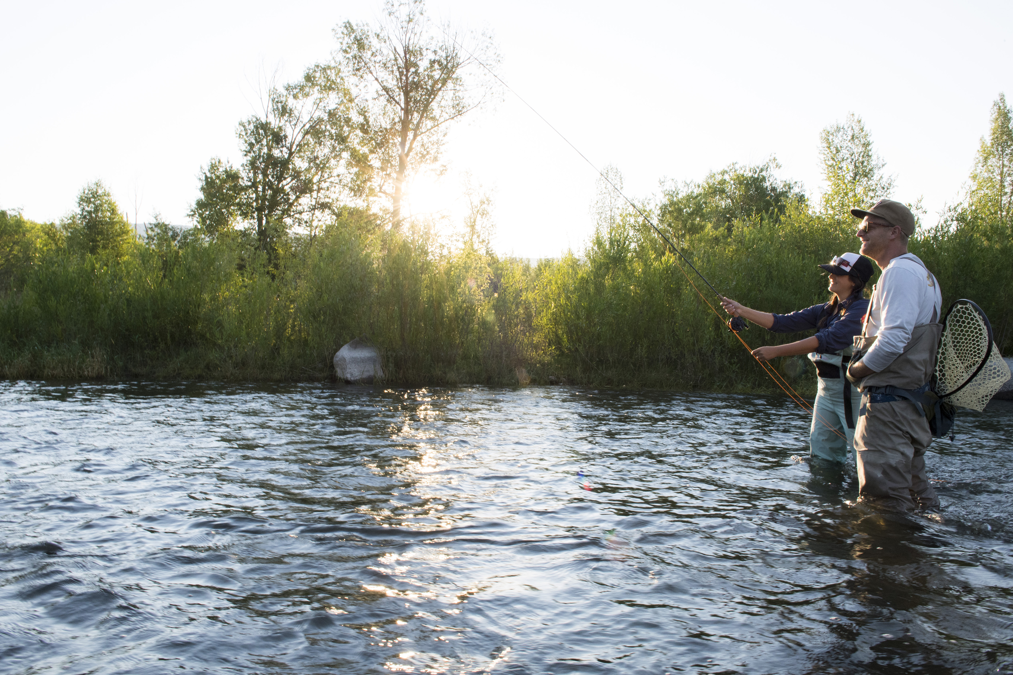 Man and woman fly fishing in the summer on the Provo River.