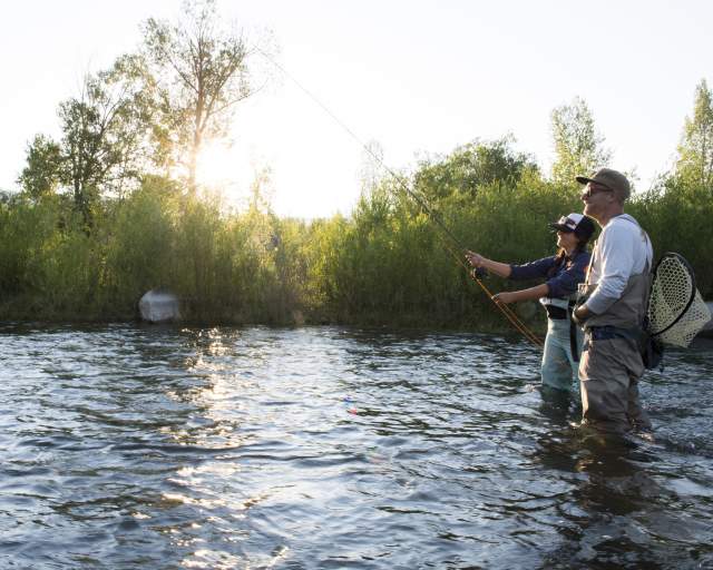 Man and woman fly fishing in the summer on the Provo River.