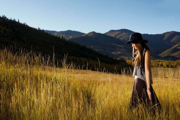 Girl Walking through field with mountains in background