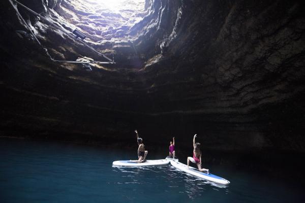 Three women doing yoga on stand up paddle boards