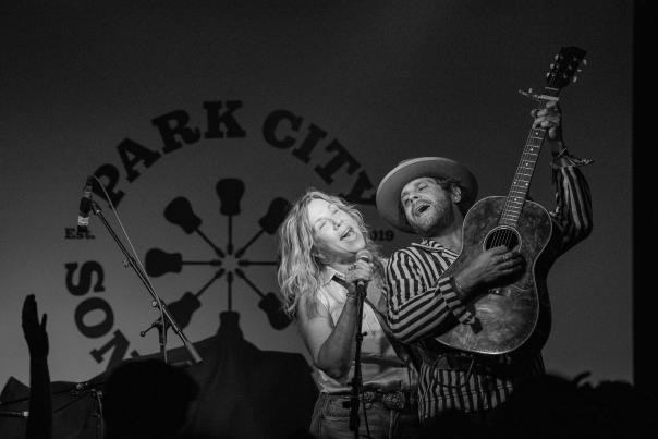 Two performers sing a song together on a stage