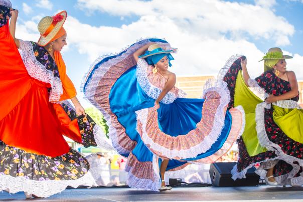 Three women dancing in elaborate dresses.