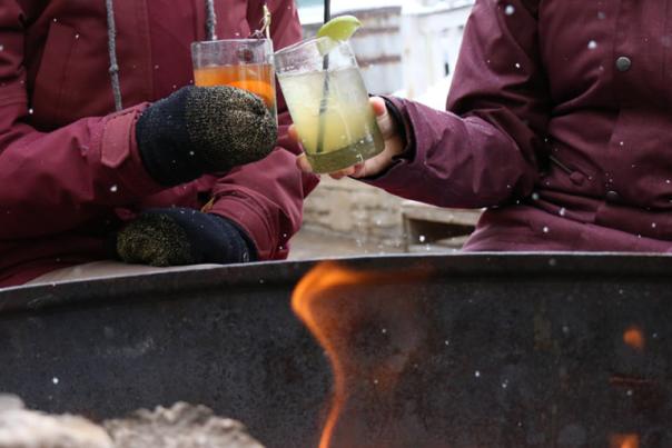 Women enjoying apres with drinks by a firepit