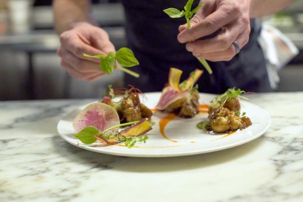 close up of hands plating a dish