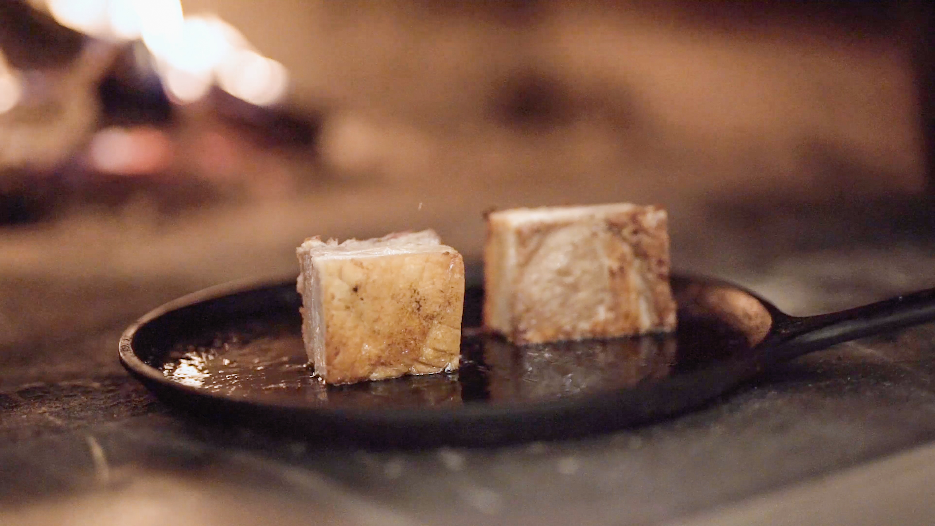 Pork belly on cast iron pan next to fire