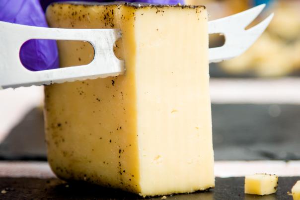 A large piece of cheese getting cut into slices